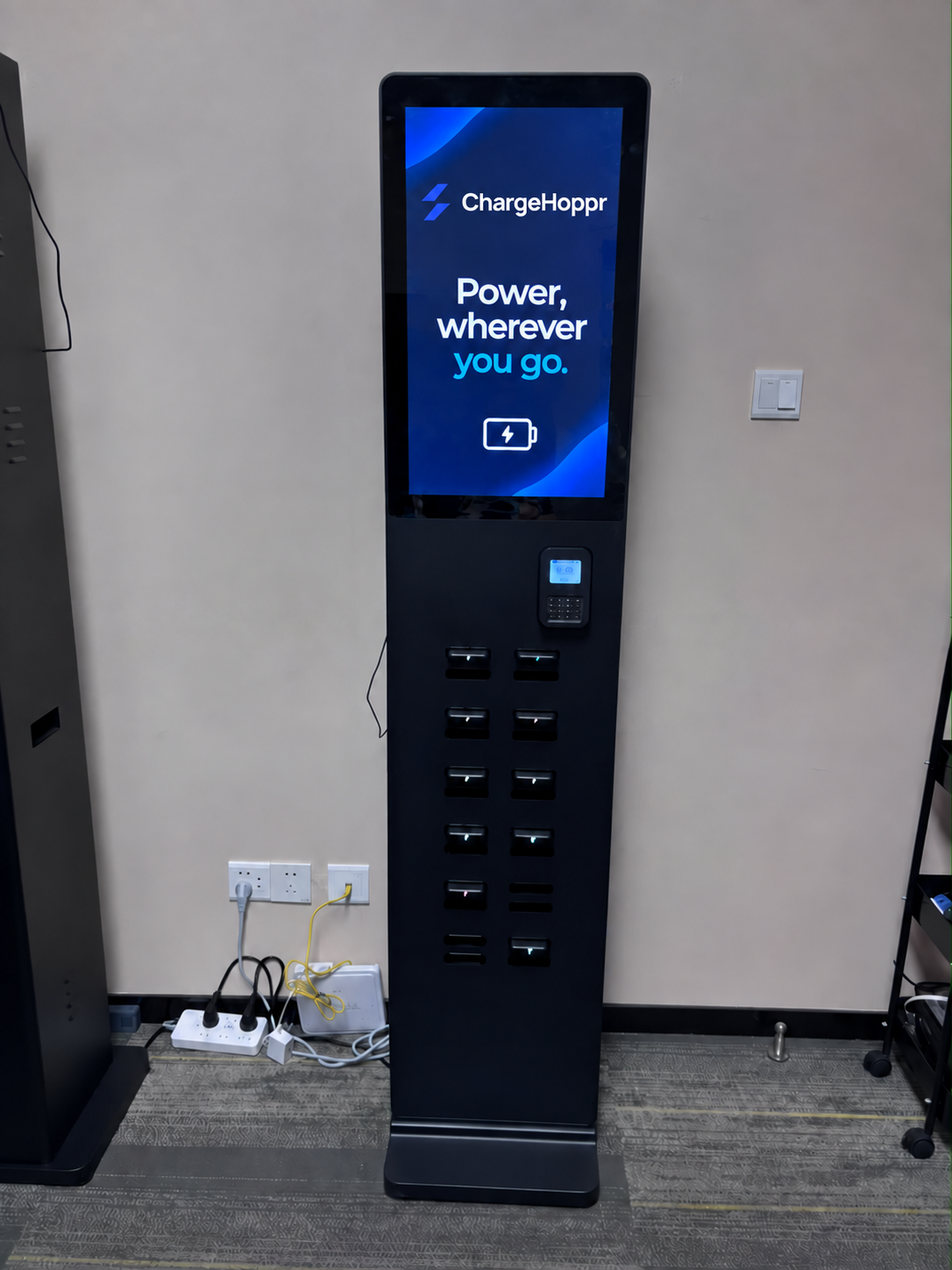 Charging station with a ChargeHoppr welcome screen, payment terminal, and portable power bank bays
